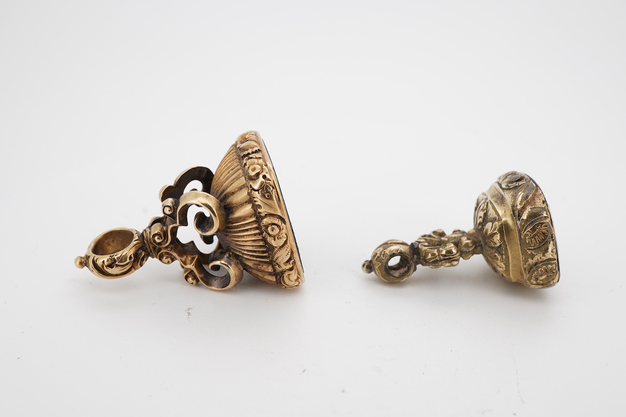 A 19th century yellow metal overlaid and bloodstone set fob seal, the matrix carved with a griffin and motto 'Opus Coronat Finis', 30mm, together with a similar gold plated fob seal and foil backed quartz fob seal, the m